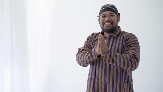 asian man with javanese traditional cloth lurik greeting and smiling to camera