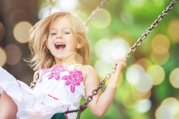Little child blond girl having fun on a swing