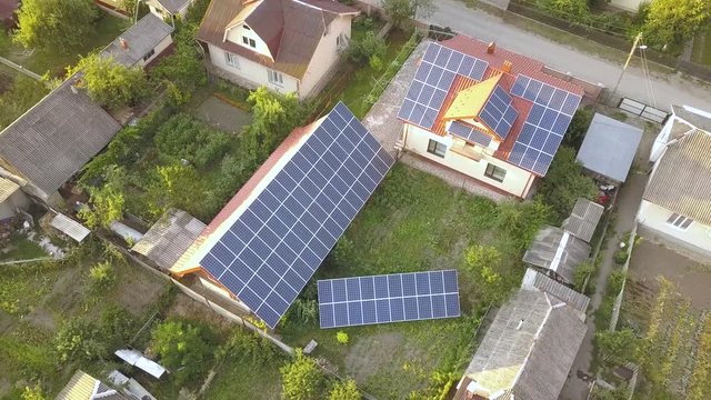 Aerial view of a private house with solar panels on roof. Photo voltaic system for renewable energy on building and on the ground.