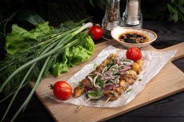 skewers of chicken on a skewer on the board on a dark background