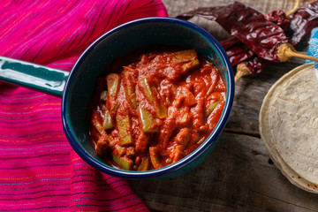 Mexican nopal cactus with guajillo red sauce on wooden background