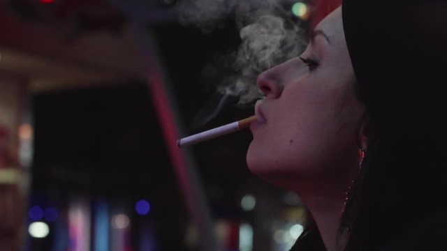 primo piano di ragazza di profilo che fuma una sigaretta al luna park