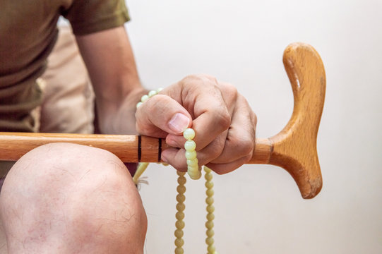 Male hand with walking stick holding praying beads
