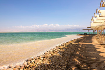 Obraz premium View of the salt-covered coastline and sun umbrellas on the Dead Sea beach
