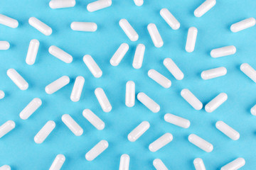 Fototapeta na wymiar white medicine capsules on blue background, view from above