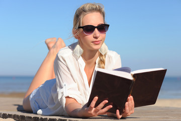 Fototapeta premium woman reads a book on the beach