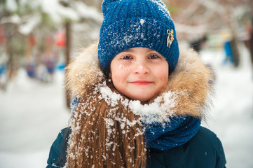 Girl in the winter forest close-up and copy space. A child plays in the winter with snow.