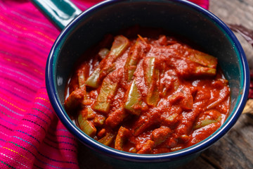 Mexican nopal cactus with guajillo red sauce on wooden background