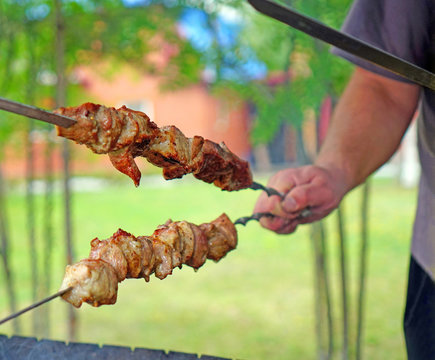 Roasting meat on skewers on the grill in the fresh air in sunny weather