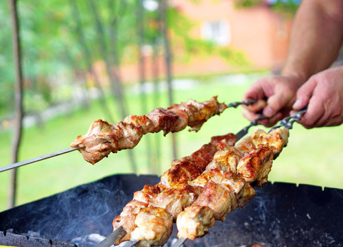 Roasting meat on skewers on the grill in the fresh air in sunny weather