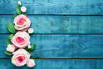 Wedding border with pink rose flowers on blue wooden background