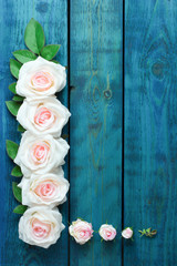 Wedding border with light pink rose flowers on blue wooden background