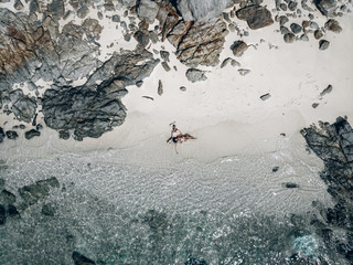 Loving couple lying on the sand at the picturesque seashore, drone shot. Happy couple concept