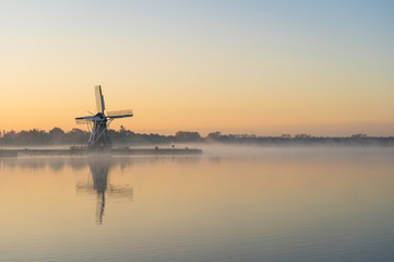 Nature awakens at a traditional Dutch windmill during a foggy dawn. De Helper, Groningen.