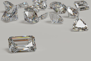 Variously cut diamonds scattered on white background with an emerald cut stone on foreground.