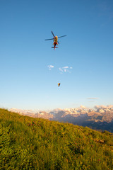 Hubschrauber, der über Landschaft gegen den Himmel in den Sonnenuntergang fliegt