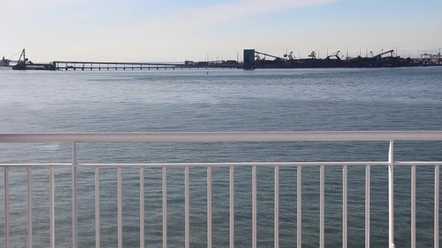 Boat Rail Passing By Water and Industrial Yard