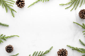 White marble table with Christmas decoration including pine branches and pine cones. Merry...