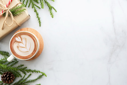 White marble table with cup of latte coffee and Christmas decoration with gift box. Christmas and new year celebration concept. Top view with copy space, flat lay.