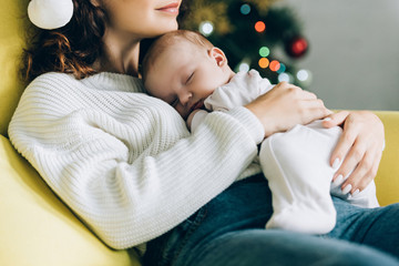 cropped view of young mother holding sleeping baby