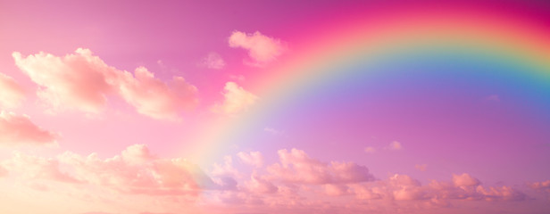 Fantasy magical rainbow on colorful sky with a lot of pink, purple and fluffy clouds. A landscape for a Unicorn.
