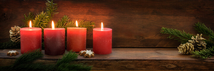 Fourth  Sunday in Advent, four burning red candles in a row, fir branches and Christmas decoration...