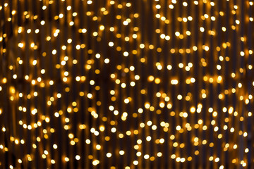 Fototapeta na wymiar Christmas and New Year golden yellow background with abstract blurred highlights. Bokeh in blur.