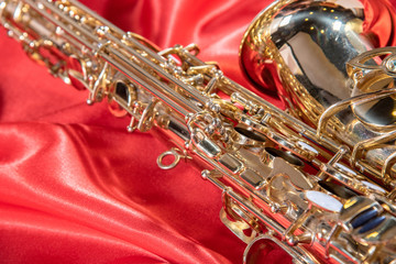 Beautiful macro photo of the details of a wind instrument of a golden alto saxophone on a red...