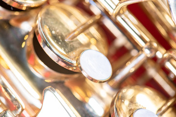 Fototapeta premium Beautiful macro photo of the details of a wind instrument of a golden alto saxophone on a red background