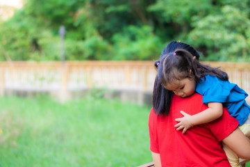 Naklejka premium An Asian mother is carrying her daughter for a walk in the park.