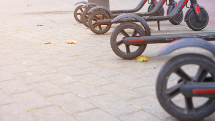 row of electric readies to ride scooter bikes in center of city on pavement stone, electric urban transportation concept