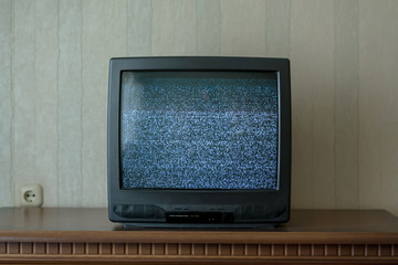 black old TV with static on screen standing on wooden table in room of home.