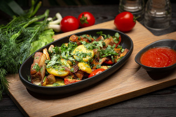 roast lamb in a black oval plate on a wooden board on a dark background