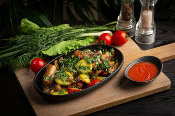 roast lamb in a black oval plate on a wooden board on a dark background