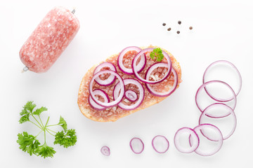 german sandwich mettbrotchen, bun and raw meat with onion and parsley on white background