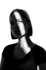 Fashionable beauty portrait. Black silhouette on white background. Girl with a spot of light on her face. 