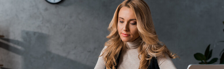 panoramic shot of attractive and blonde businesswoman looking down