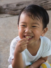 Asian child boy eating food with smiling happy funny close up face. Young kid laughing. Family relax and freedom time in summer holiday.