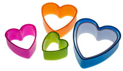 Hearts, colored plastic molds for dough slicing in the form of cookies, on a white background.