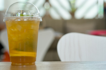 Plastic glass of tea lemonade on wooden table