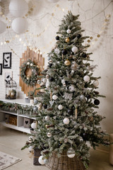 Modern black and white interior design room with Christmas and New Year decorations, toys, gifts, snow-covered fir tree, garlands. Winter holidays composition.