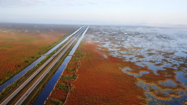 Flying over a highway in a paramotor surrounded by streams and wetlands in the Florida everglades