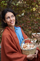  Young woman with a basket of eggs outdoors.