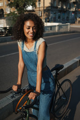 Fototapeta na wymiar African woman walking outdoors with bicycle by street.