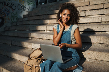 Woman sit on steps listening music.