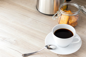 Coffee in a cup on the table and cookies in a glass jar and kettle, morning drink, breakfast, copy space.