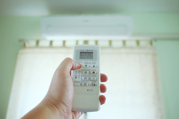 Air conditioner inside the room with man open or close remote controller.  Air conditioner with remote controller