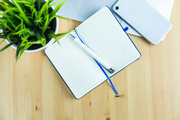 Notatnik, długopis, telefon smartphone na drewnianym stole, widok z góry © kashanowa