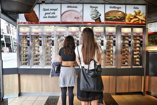 AMSTERDAM, NETHERLANDS - JULY 10, 2017: Customers choose their fast food in Febo in Amsterdam. Febo is a popular self service Dutch fast food chain specializing in croquettes and burgers.