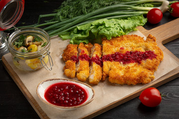 chicken schnitzel on a board with herbs and sauce in a cup